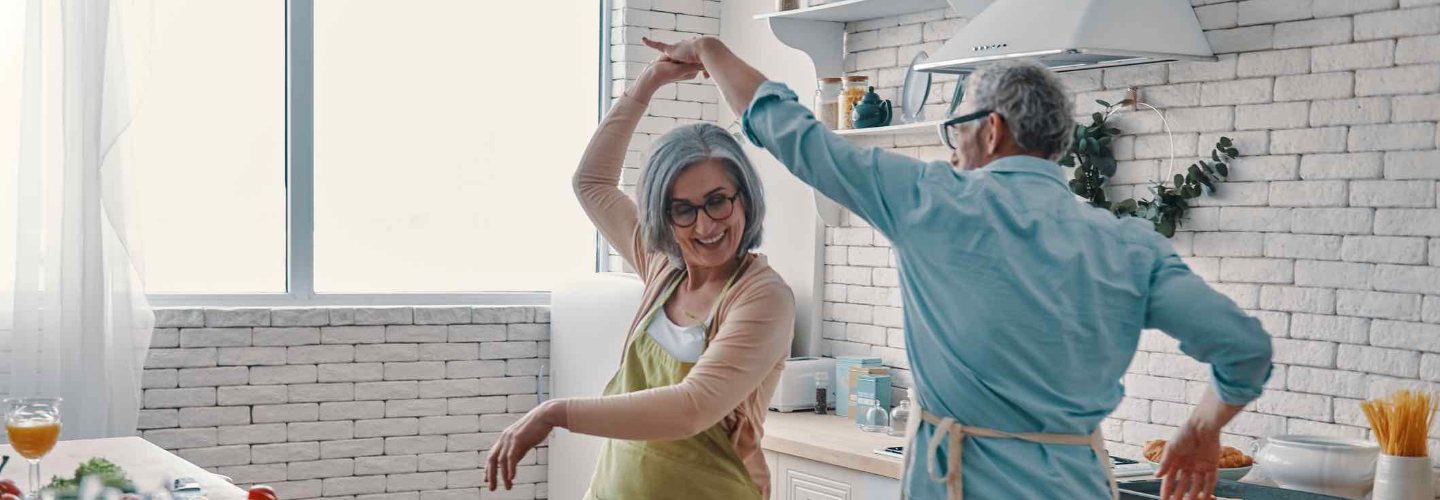 an elderly couple dancing in their kitchen