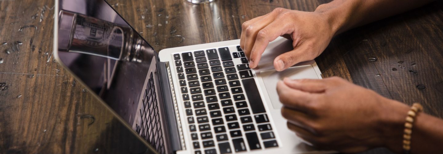 a person's hands typing on their laptop