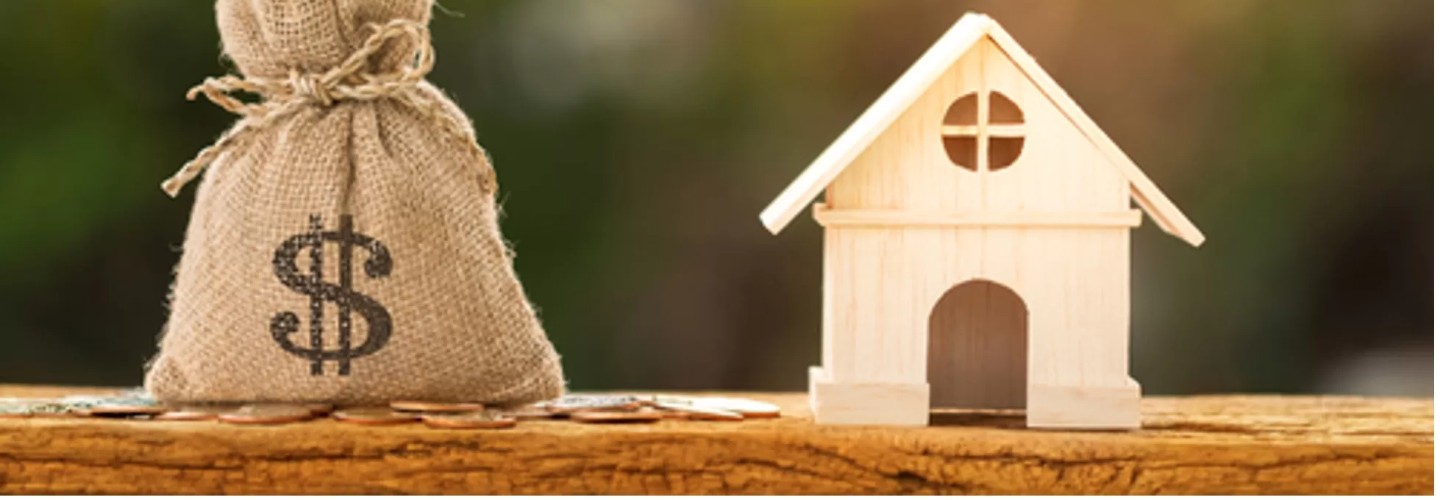 money bag next to a small wooden model house